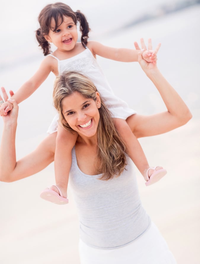 Beautiful mother carrying her daughter on shoulders at the beach Beautiful mother carrying her daughter on shoulders at the beach